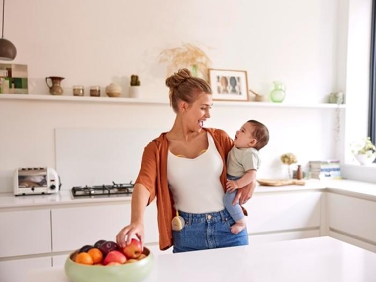 Freestyle™ Hands-free double electric wearable breast pump A mom holds her baby and has a snack while wearing her Medela Freestyle™ Hands-free double electric breast pump.