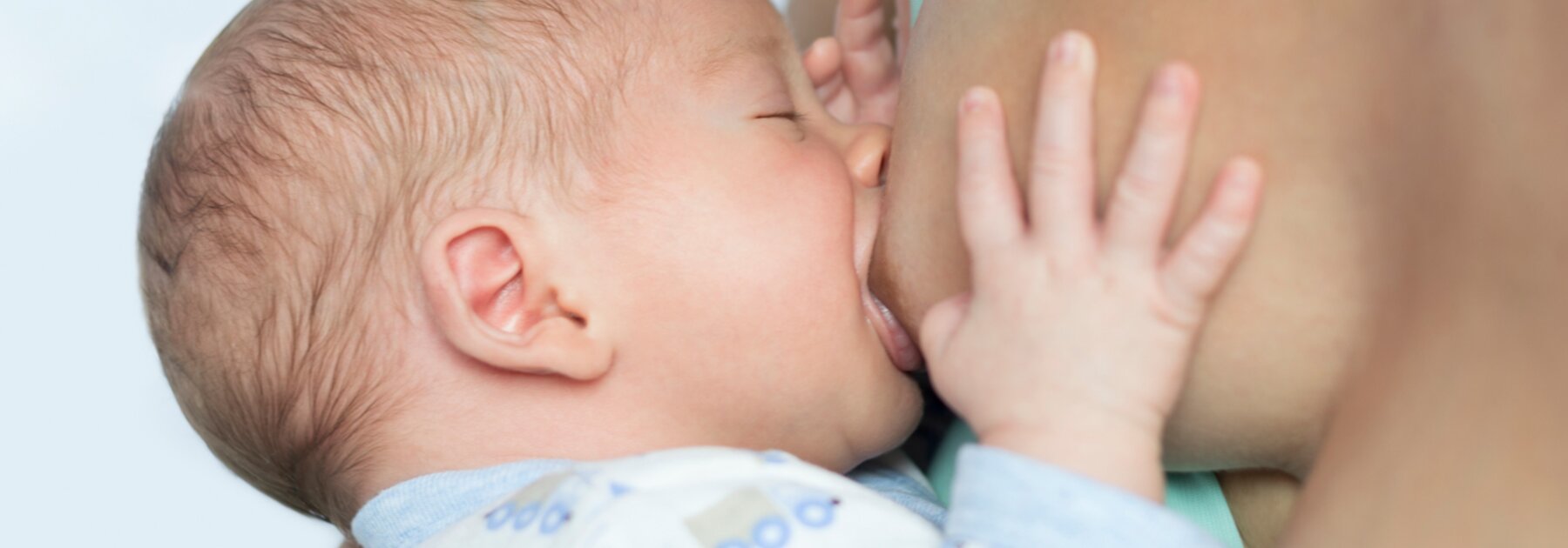 Baby drinking breast milk directly from mother's breast during breastfeeding session