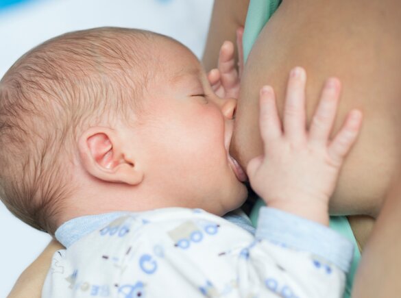 Baby drinking breast milk directly from mother's breast during breastfeeding session