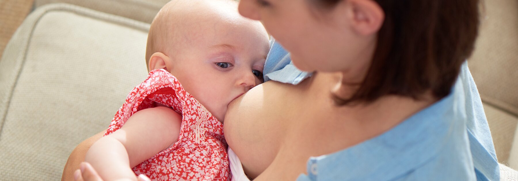 A mother is at home breastfeeding her baby.
