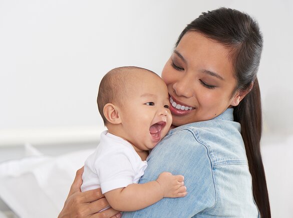 Breastfeeding Challenges A mom holds her happy baby and smiles.