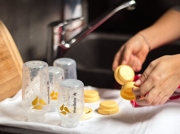 A mother washes Medela breast milk bottles and lays them on a towel to dry.