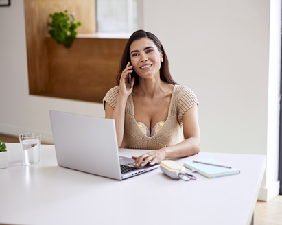 Mother wearing a Medela Freestyle™ Hands-free double electric wearable breast pump while using her phone