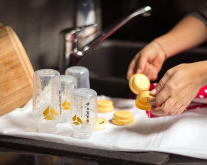 A Mom washing breast milk storage bottles and putting them on a towel to air dry