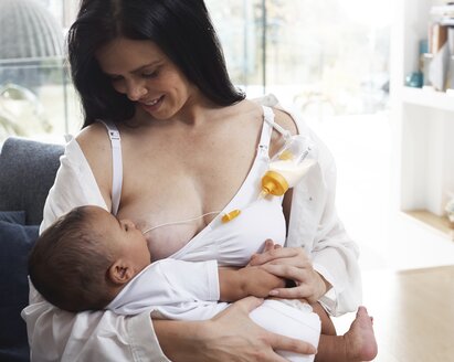 A mom breastfeeding her baby and supplementing the diet using Medela's Supplemental Nursing System™ (SNS).