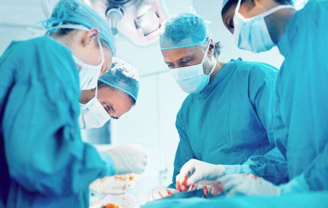 Salle d'opération avec plusieurs médecins regardant un patient.