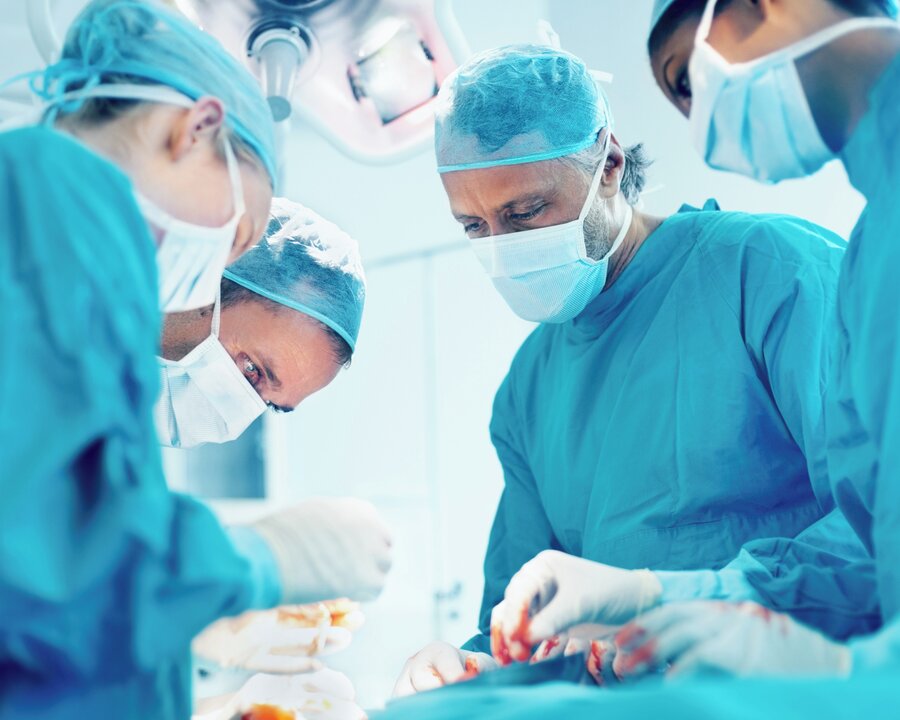 Salle d'opération avec plusieurs médecins regardant un patient.