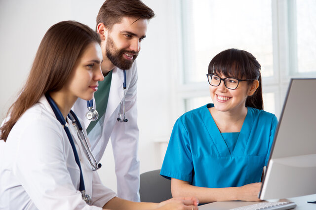 Groupe de trois professionnels de la santé travaillant ensemble et regardant un écran d'ordinateur.