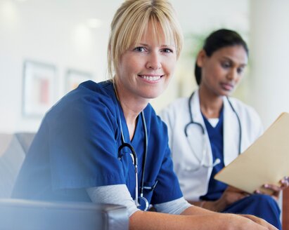 One doctor smiling at camera other doctor looking at a chart.