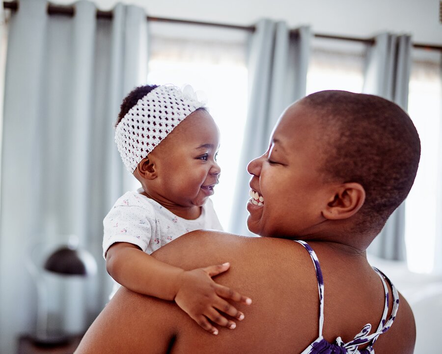 Mother holding baby and both smiling at one another