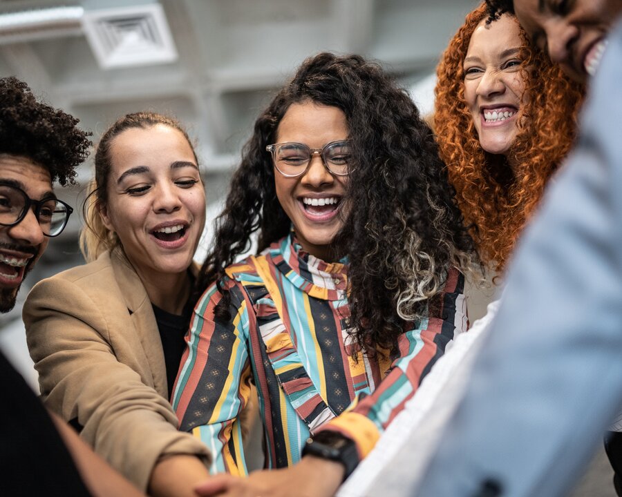 Group of colleagues all putting their hands together in the center of the group.