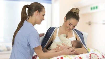 Nurse and mom with shirt open while nursing her baby.