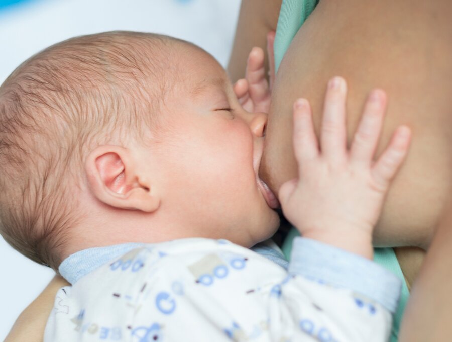 Baby drinking breast milk directly from mother's breast during breastfeeding session