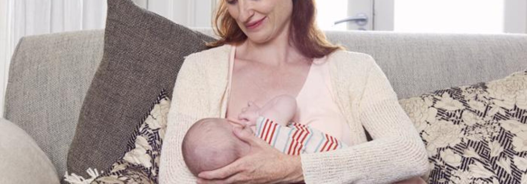 Mother breastfeeding baby in cross-cradle hold.