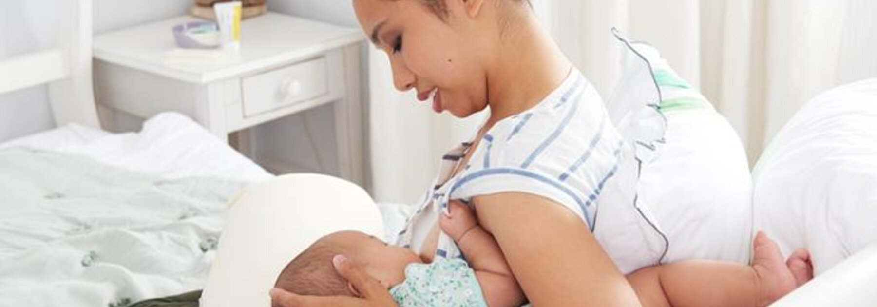 Mother breastfeeding baby in rugby ball hold.