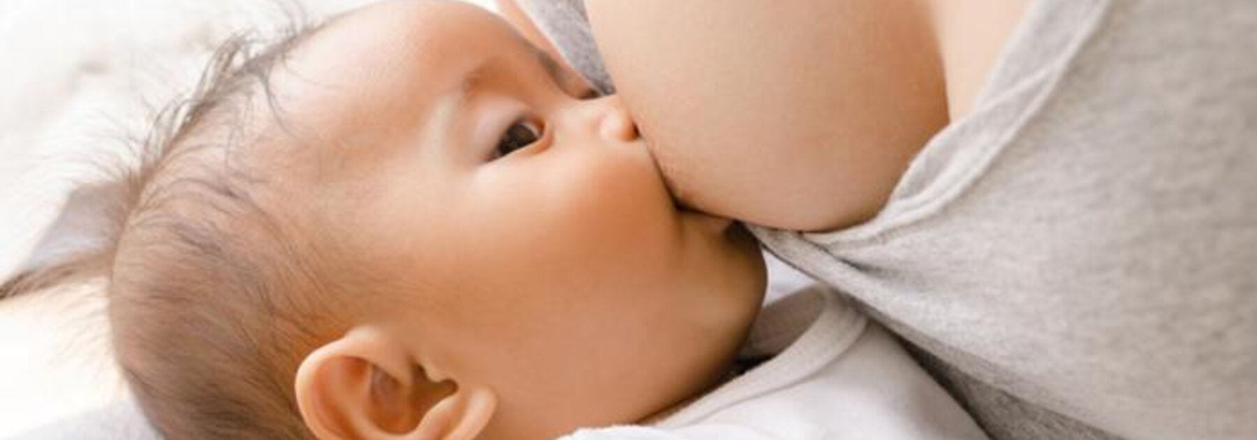 Mother breastfeeding baby in dangle feeding positioin.