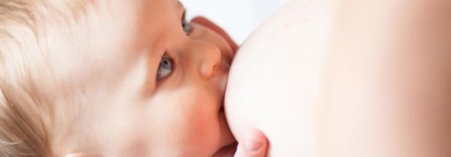 Mother breastfeeding baby in dancer hand nursing position.