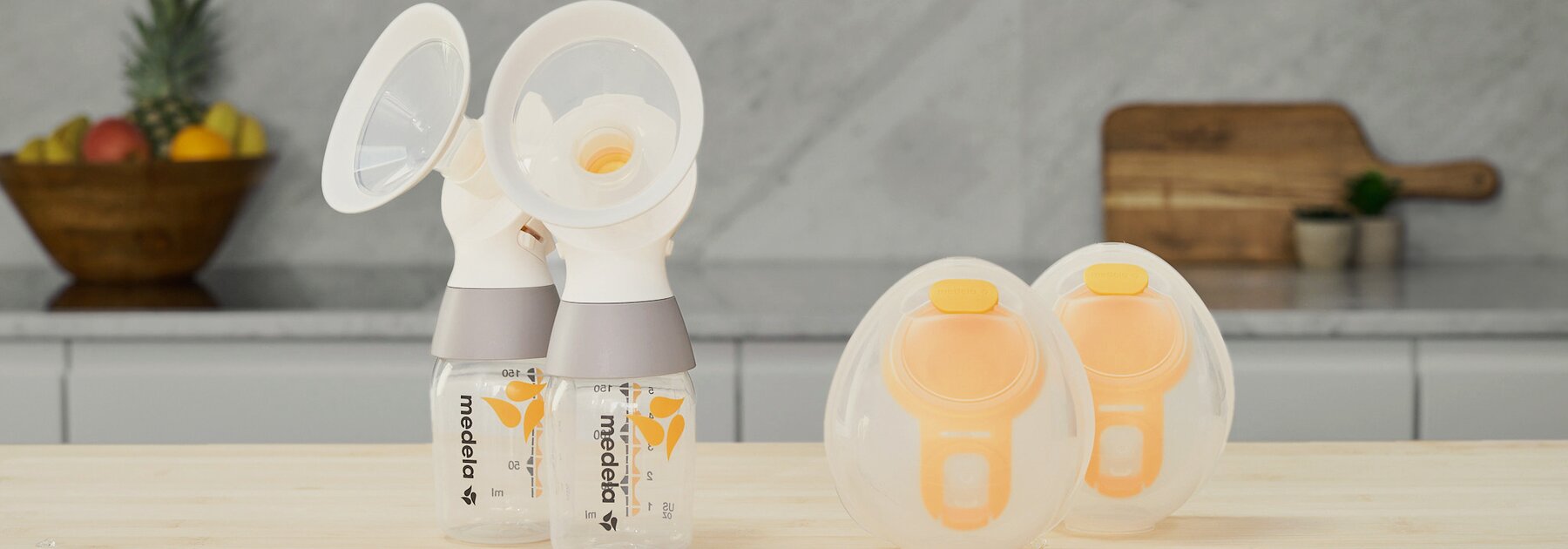 A set of Medela Hands-free Collection Cups with a Medela classic PersonalFit Flex™ double pumping kit, tubes not shown, sitting on a counter.