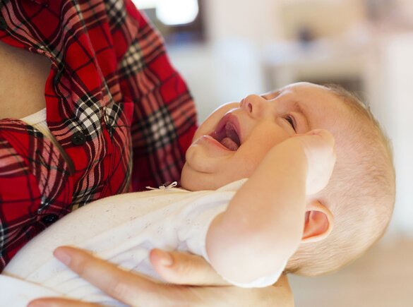 Ein Baby weint in den Armen seiner Mutter, während sie versucht, es zu stillen.